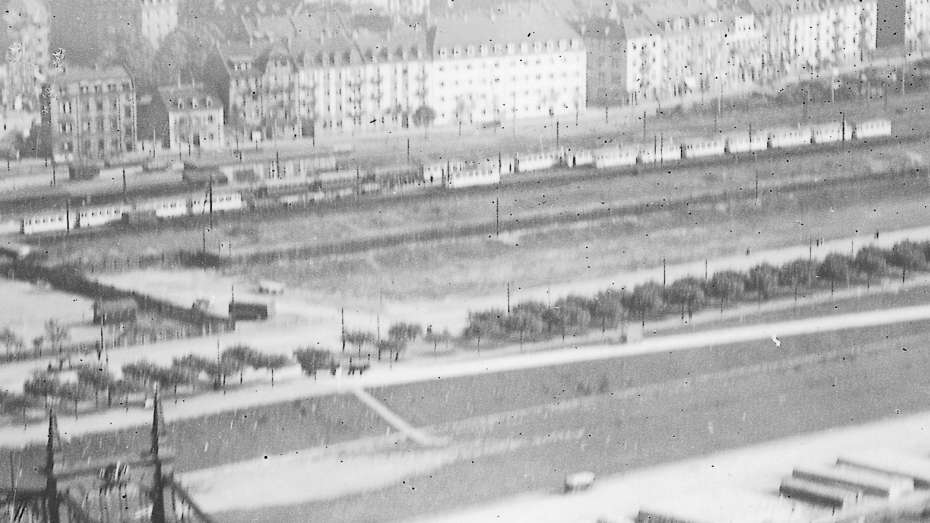schwarz-weißes Luftbild von 1927 mit der Friedrichsbrücke (heute Kurpfalzbrücke). Oben rechts die Alte Feuerwache und dahinter das Neckarufer mit Beginn des Teilstücks „Weißer Sand“